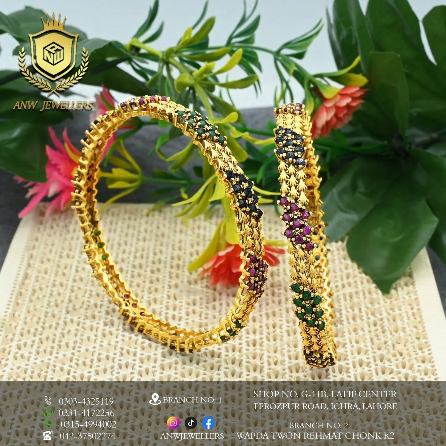 Gold bangles with colorful gemstones by ANW Jewellers, displayed with green leafy background