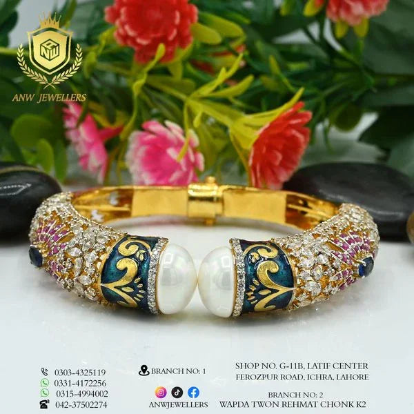 Gold bangle with gemstone and pearl detailing by ANW Jewellers, floral background
