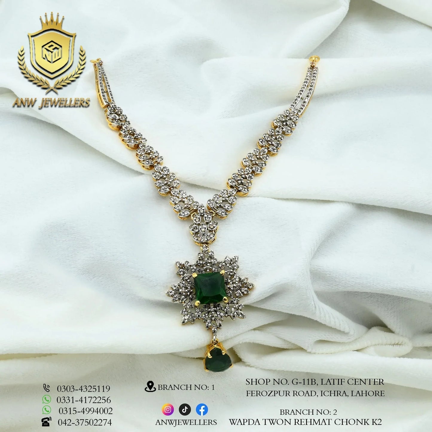 Gold necklace set with green gemstone and diamond accents by ANW Jewellers on white fabric.