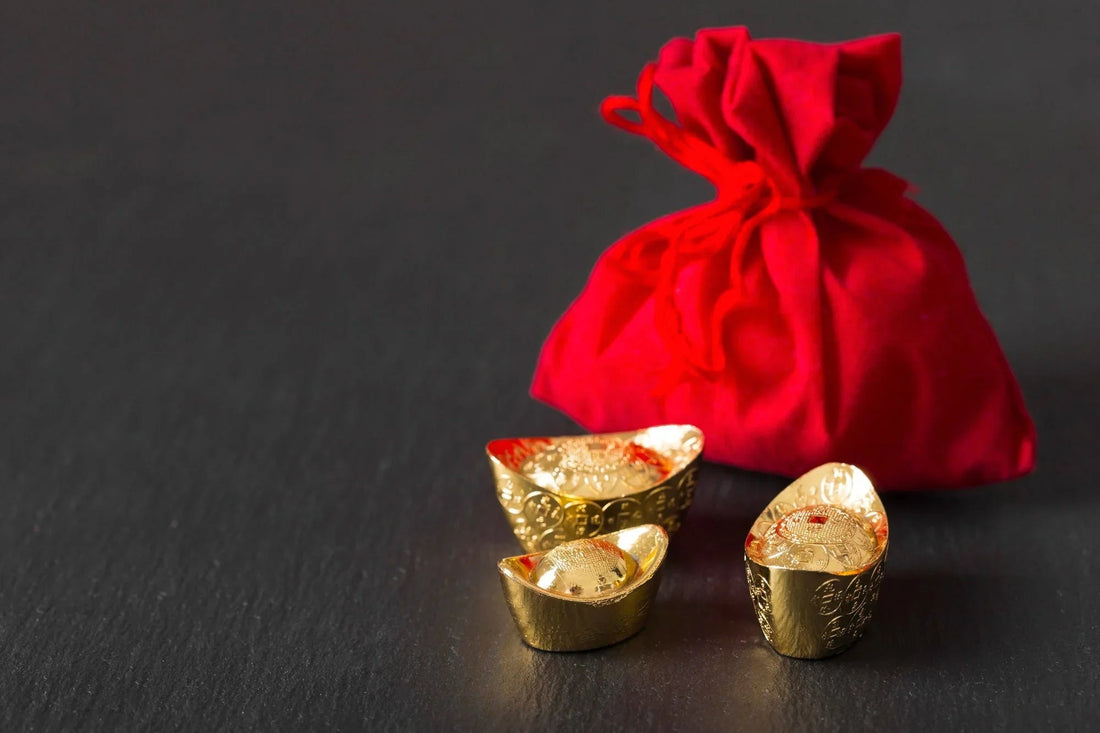 Gold ingots and red pouch on black background, symbolizing wealth and prosperity