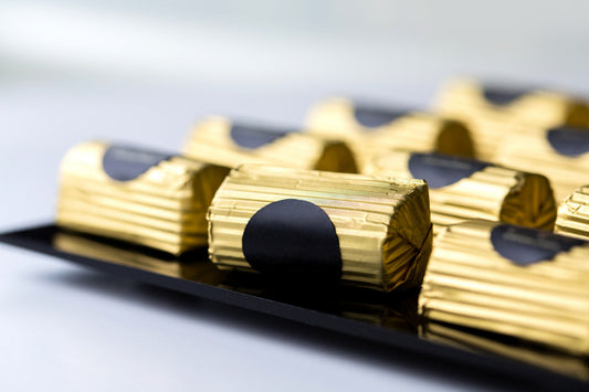 Gold foil wrapped chocolates arranged on a tray, close-up view.