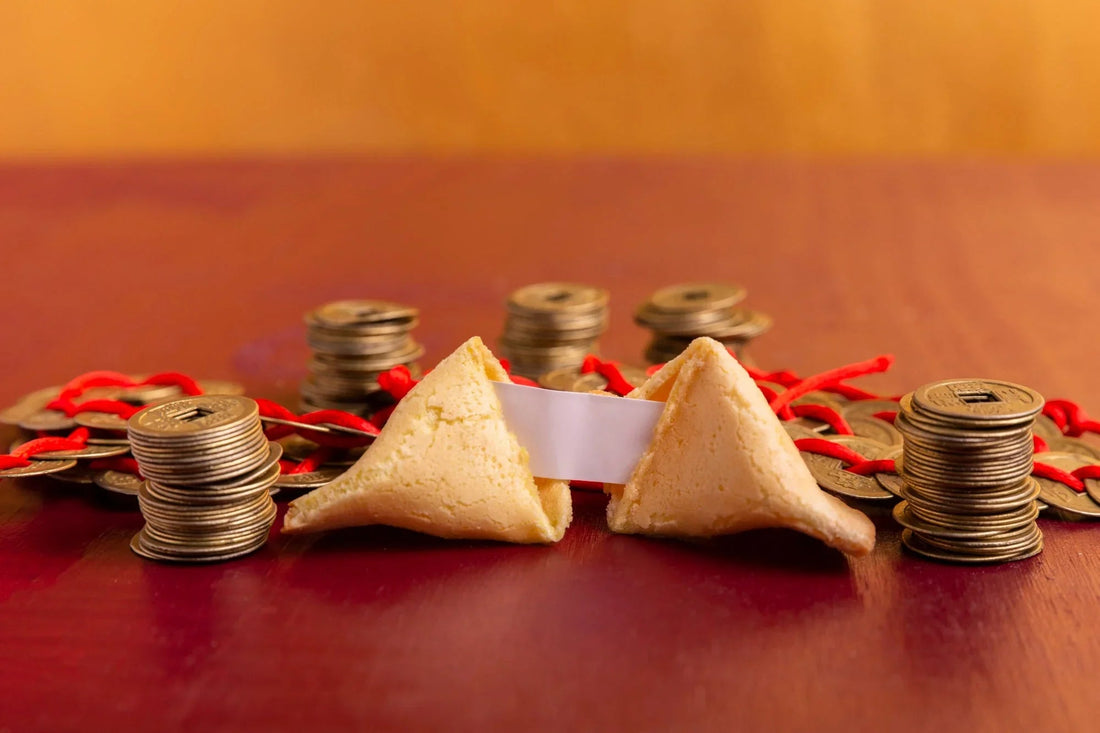 Fortune cookie with paper slip and stacks of Chinese coins on red and orange background