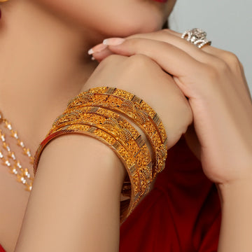 Woman wearing intricate gold bangles and rings, jewelry close-up on hands