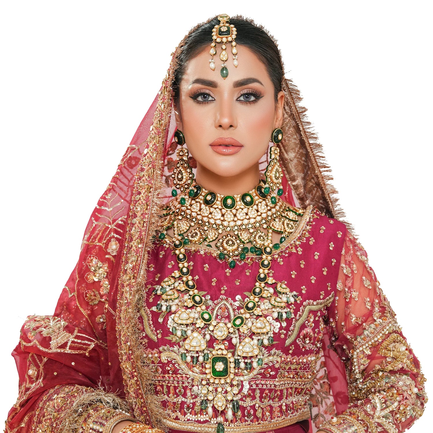 Bride in traditional red bridal attire with gold and green jewelry set